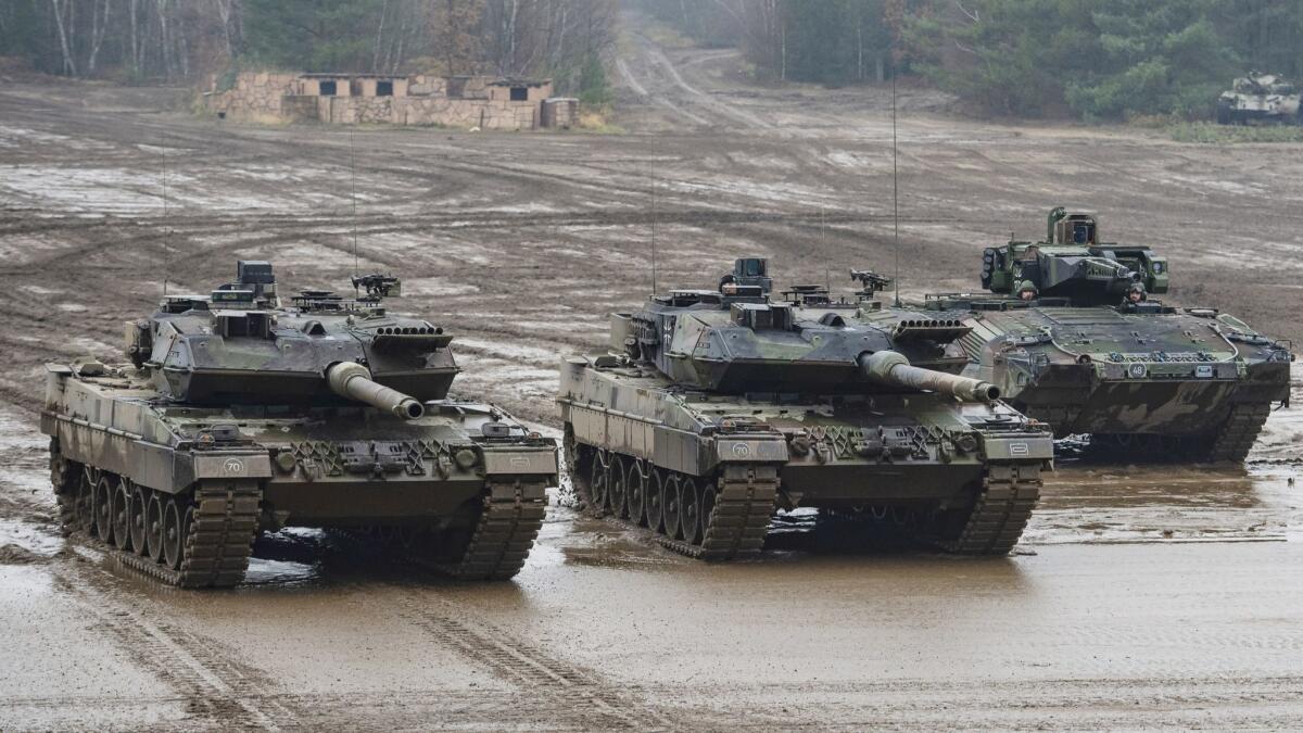 Two German Bundeswehr main battle tanks, type Leopard 2A6 and a Puma infantry fighting vehicle during a December 2018 exercise in Munster, Germany.