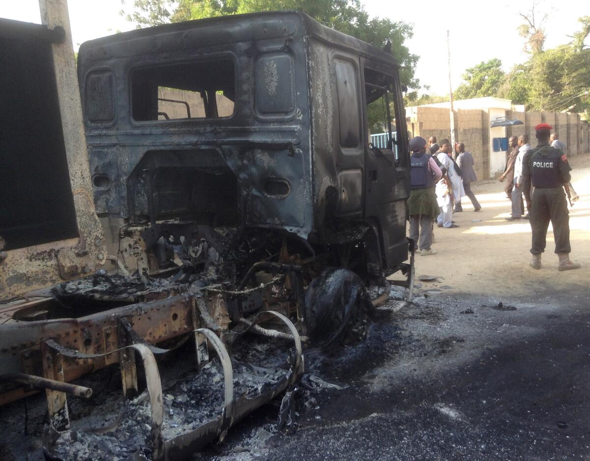 Police stand guard beside a burned-out truck following an attack Monday by Boko Haram militants in Maiduguri, Nigeria.