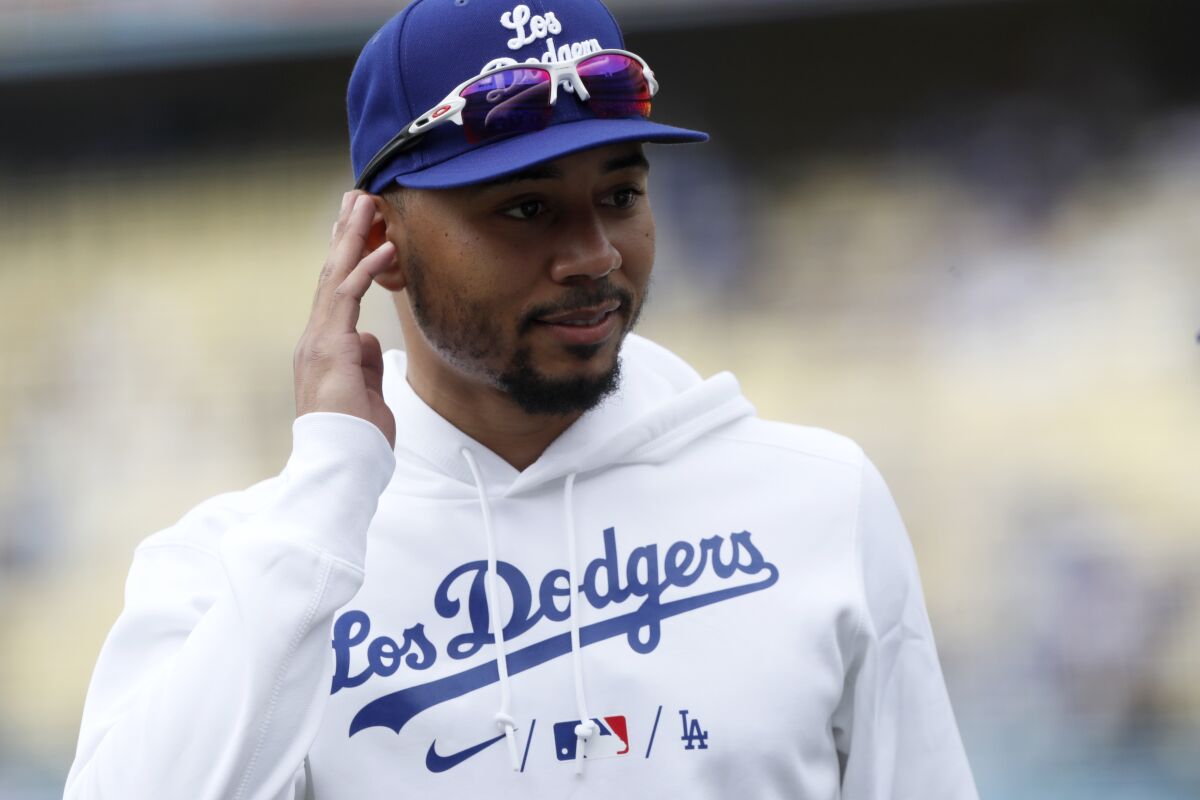 Los Angeles Dodgers' Mookie Betts talks to a fan while wearing a new Los Dodgers warm up uniform.