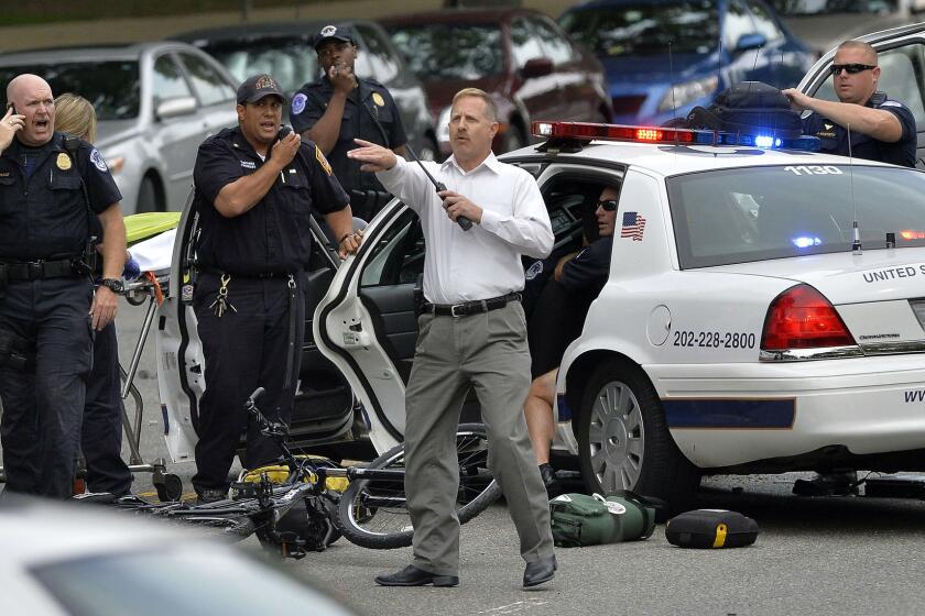 Police officers attend to an officer in a cruiser that was wrecked after shots fired were reported near the U.S. Capitol in Washington.