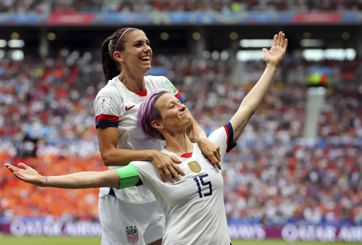 Megan Rapinoe strikes her iconic pose after scoring a goal in the opening game of the 2019 World Cup as U.S. teammate Alex Morgan leaps on her back.