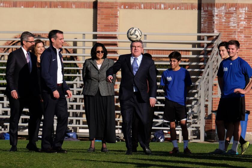 International Olympic Committee President Thomas Bach, center, plays with a soccer ball while watched by Los Angeles Mayor Eric Garcetti, third from left, and UCLA students during a visit to the university.