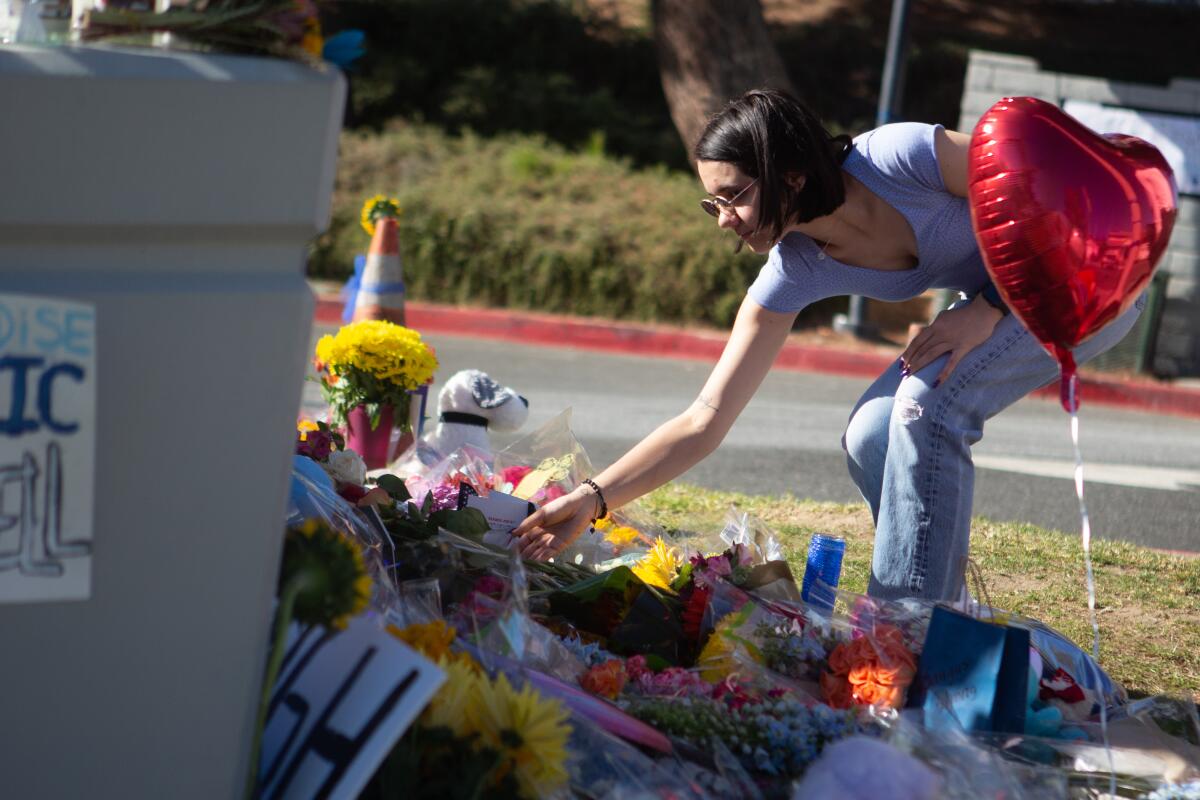 A mourner places flowers at a memorial for victims of the Nov. 14, 2019, Saugus High School shooting.
