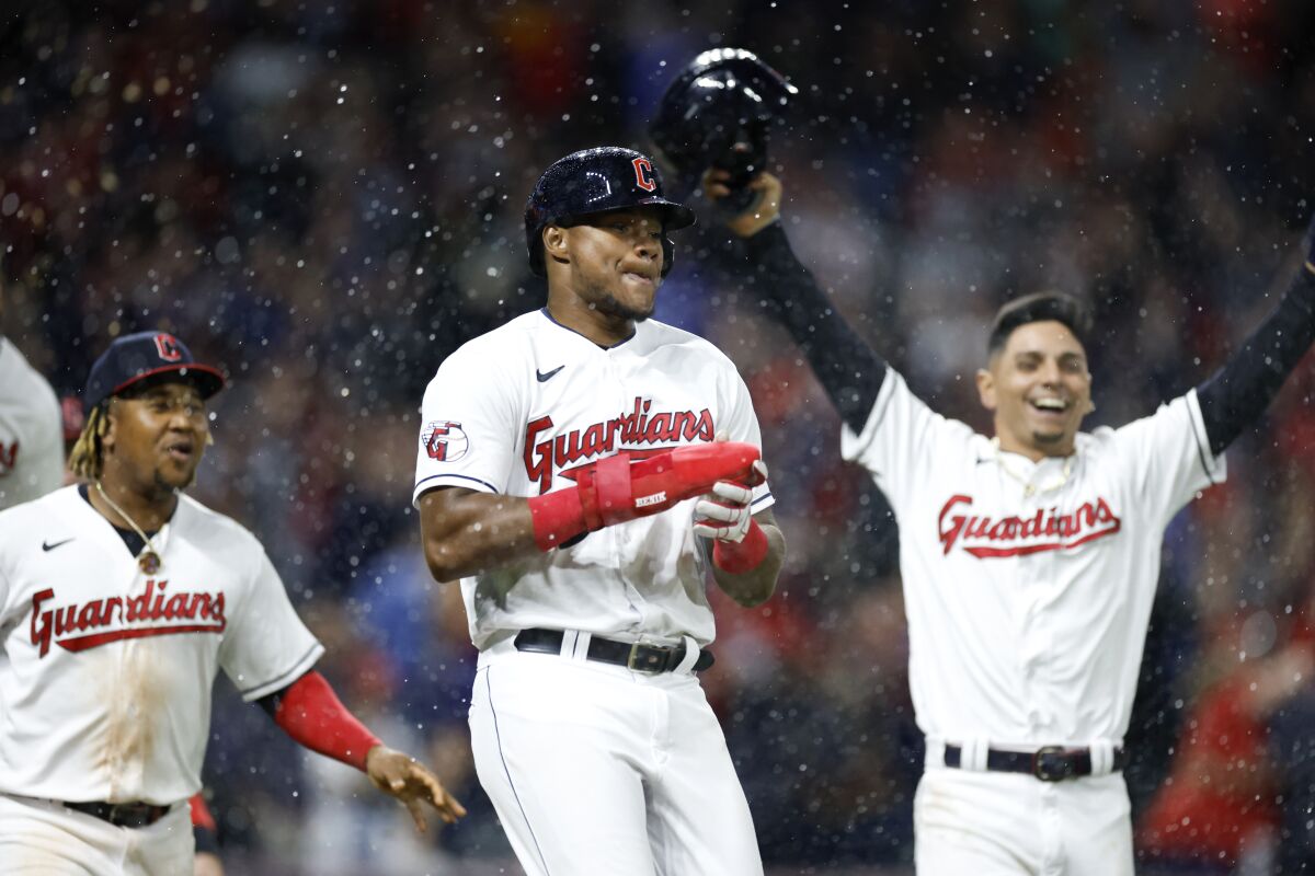 Cleveland Guardians' Oscar Gonzalez, center, celebrates with José Ramírez, left, and Andrés Gimenez, right, after scoring the winning run against the Oakland Athletics during the ninth inning of a baseball game, Friday, June 10, 2022, in Cleveland. (AP Photo/Ron Schwane)