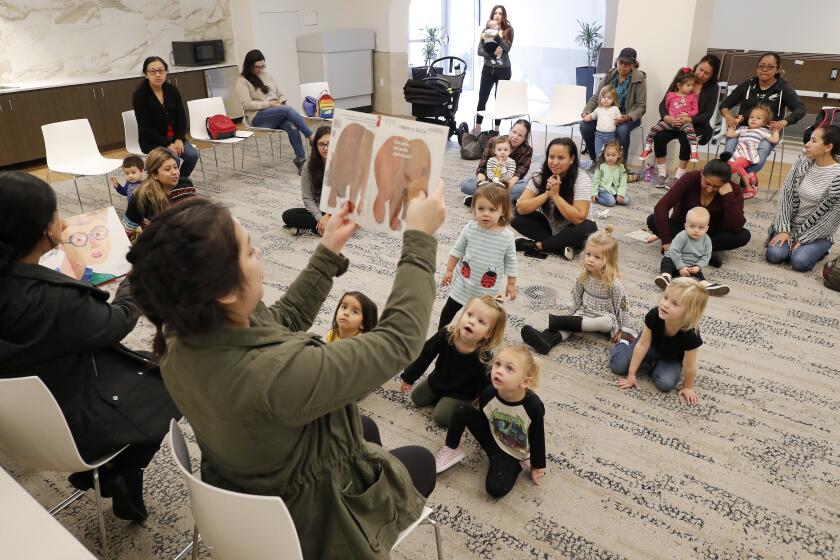 Attendees listen as library staff members Liana Lujan, bottom right, and Rosalba Rivera, bottom left, read stories in English and Spanish during Bilingual Storytime at Donald Dungan Library in Costa Mesa on Thursday.