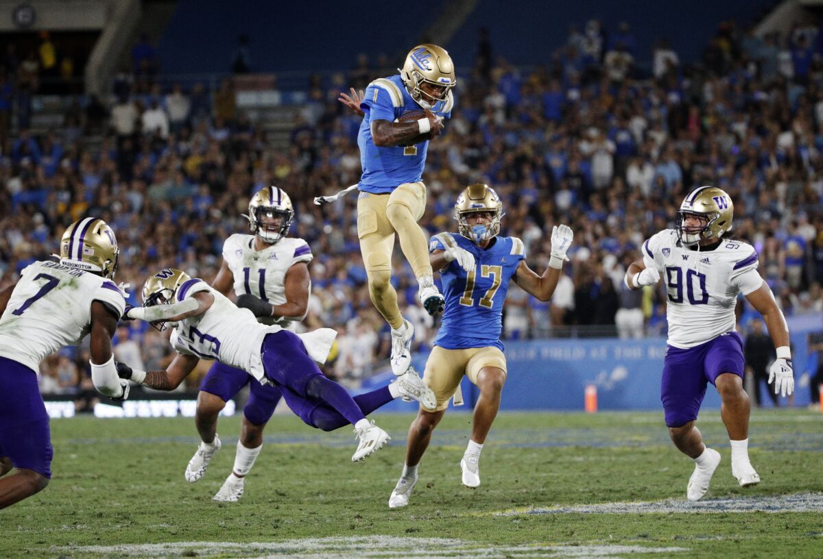 Le quart-arrière de l'UCLA, Dorian Thompson-Robinson, saute par-dessus la défense de Washington.