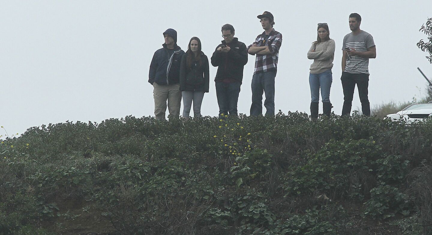 Onlookers watch from a bluff overlooking Pacific Coast Highway as investigators examine the scene of the accident.