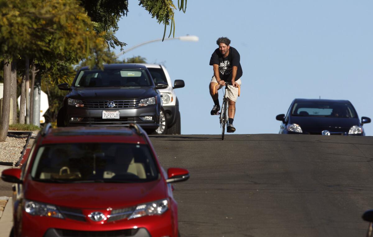 A bicyclist rides down a San Diego street. The city is planning to remove parking on some streets to make way for protected bike lanes.