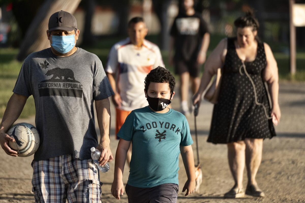 ARCHIVO – En esta fotografía de archivo del 9 de mayo de 2020, algunos adultos y niños utilizan mascarillas 