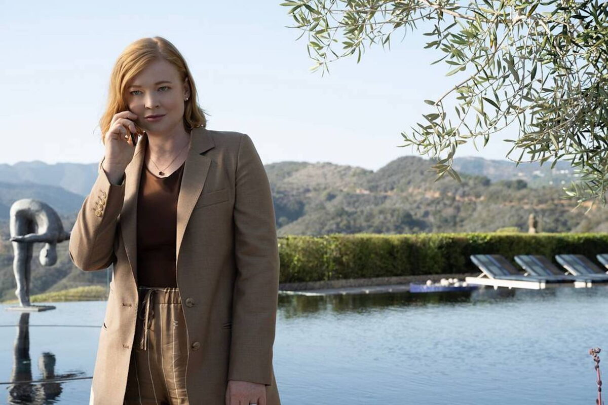 A woman stands by a swimming pool, talking on a cellphone