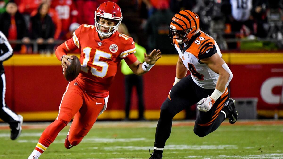Kansas City Chiefs' Patrick Mahomes (15) rushes away from Cincinnati Bengals' Sam Hubbard (94) after protection broke down during the first half on Sunday.
