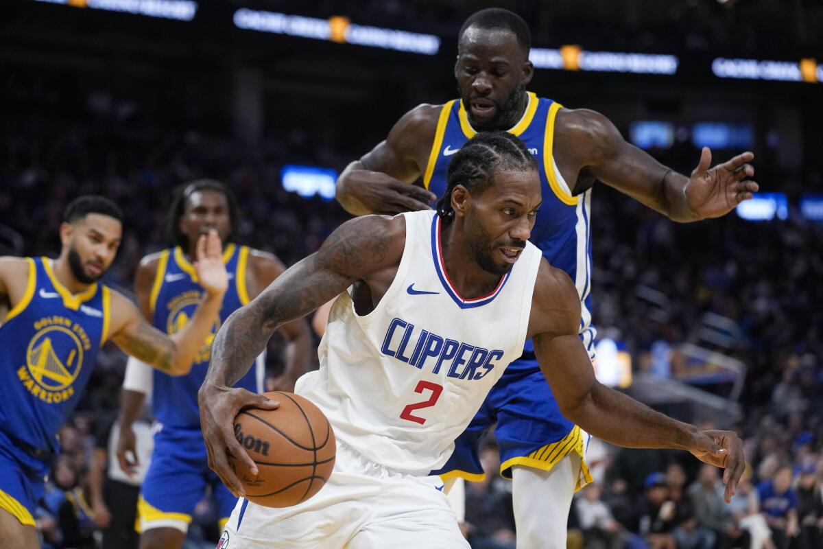 Clippers forward Kawhi Leonard moves the ball while defended by Warriors forward Draymond Green during Thursday's game.