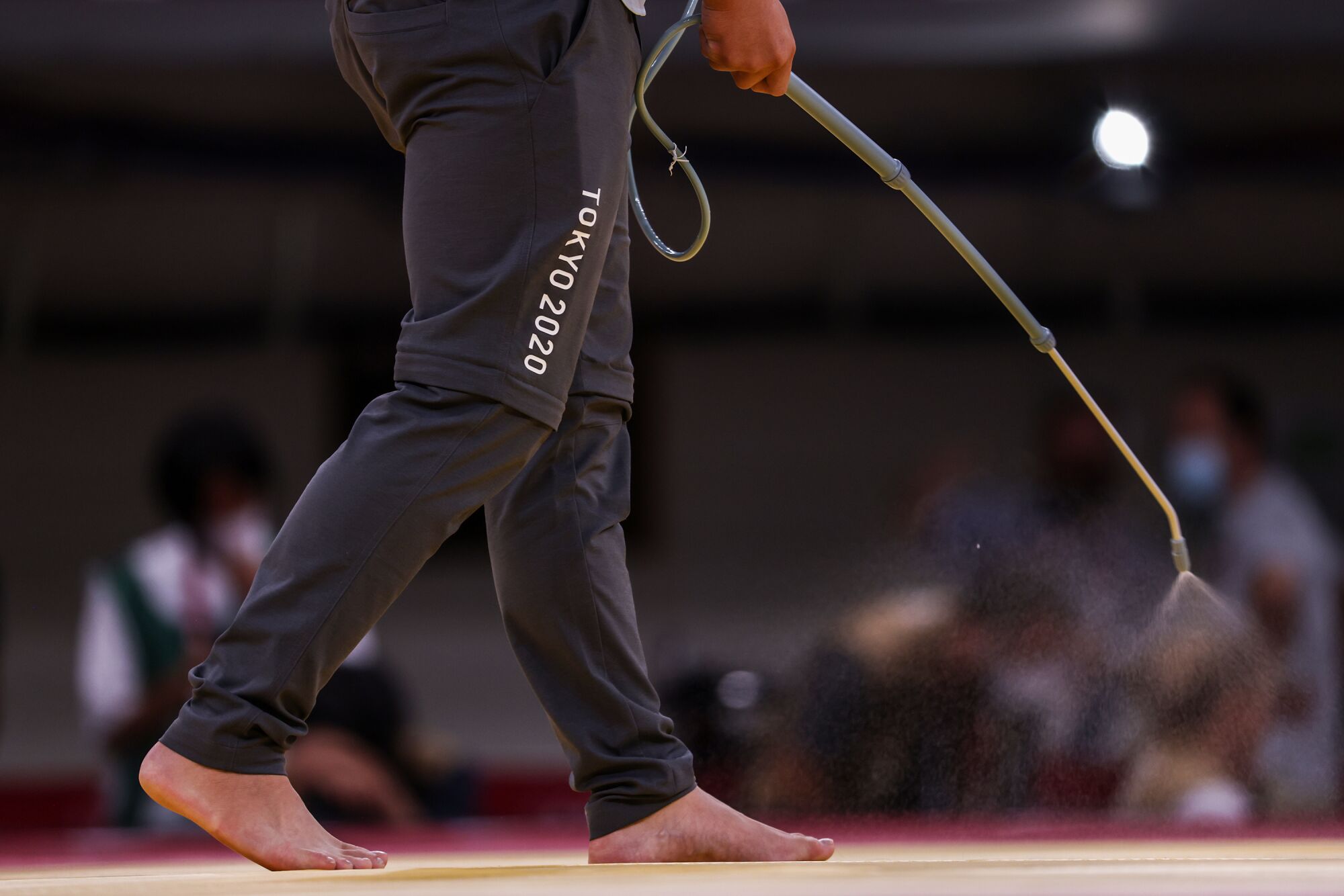 A worker sprays disinfectant between matches at the judo finals