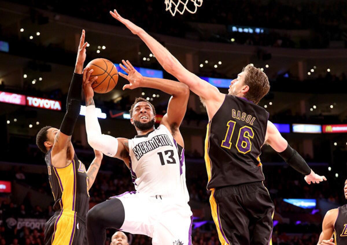 Kings forward Derrick Williams tries to score between the defense of Lakers power forward Pau Gasol (16) and guard Kent Bazemore in the first half Friday night at Staples Center.