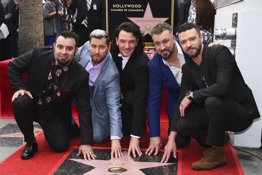 NSYNC's Chris Kirkpatrick, Lance Bass, JC Chasez, Joey Fatone and Justin Timberlake smile and crouch by a Walk of Fame star