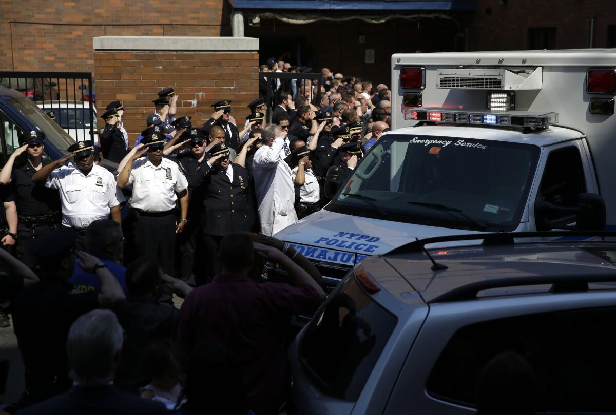 New York police officers salute as the body of Officer Brian Moore is carried away from Jamaica Hospital in New York on Monday.