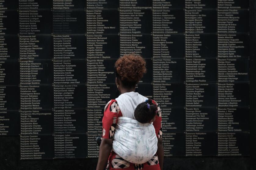 A woman at the Kigali (Rwanda) Genocide Memorial, which features a wall of victims' names.