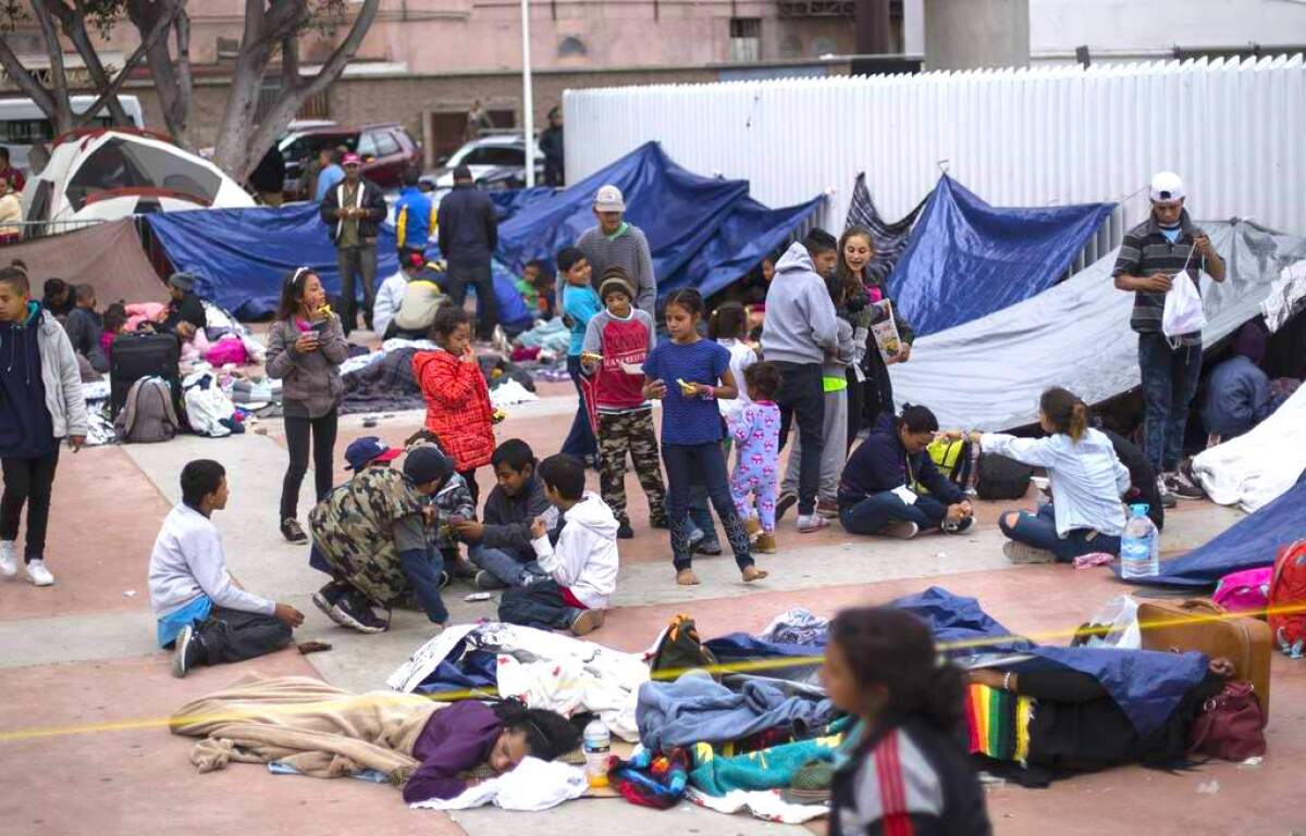 Migrantes esperan afuera de un cruce fronterizo en Tijuana, México.