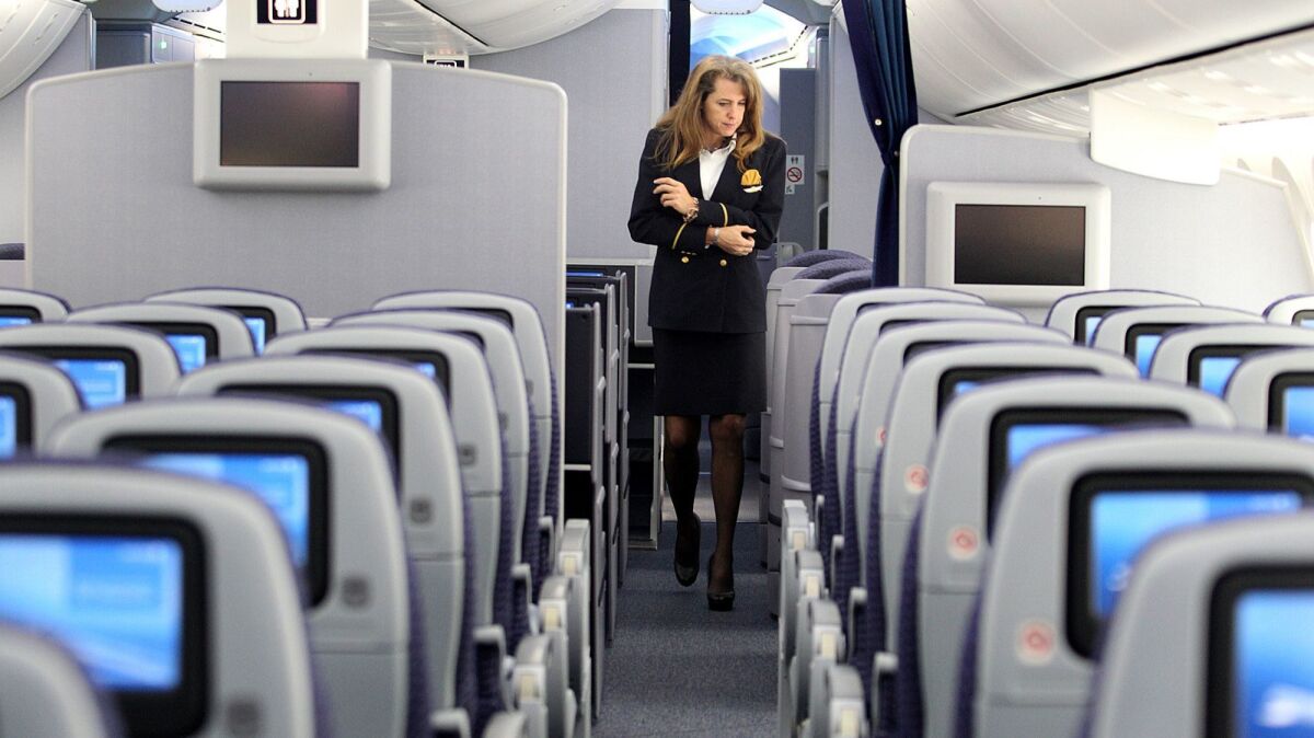 Flight attendant Tonya Johnson walks along the aisles of United Airlines' 787 Dreamliner at Los Angeles International Airport on Friday, Nov. 30, 2012. United flight attendants will begin Sept. 1 to pitch passengers on a co-branded credit card.