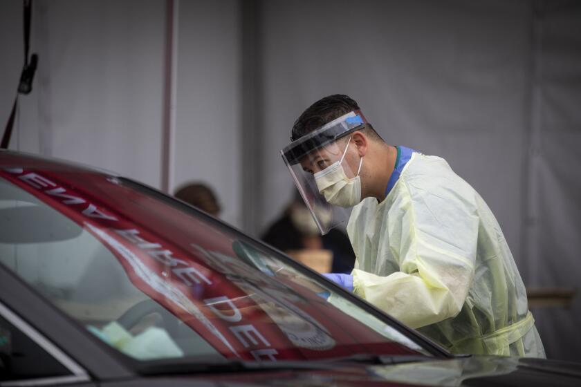 PASADENA, CA - MAY 18, 2020: Health care works speak with drivers at the drive thru coronavirus testing site in parking lot B of the Rose Bowl in Pasadena, CA on Monday, May 18, 2020. The coronavirus infection rates are going down in California however the infection rate has not deceased enough. (Francine Orr/ Los Angeles Times)
