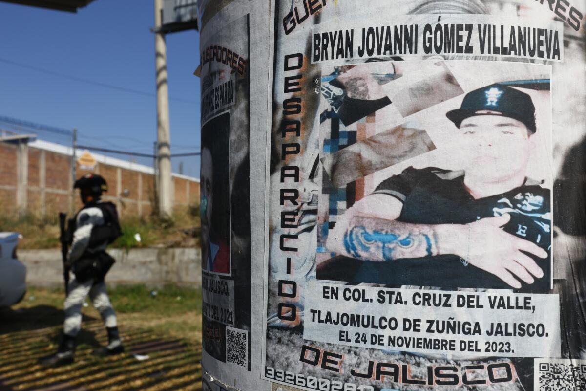 Members of the Mexican National Guard patrols near a poster of a man