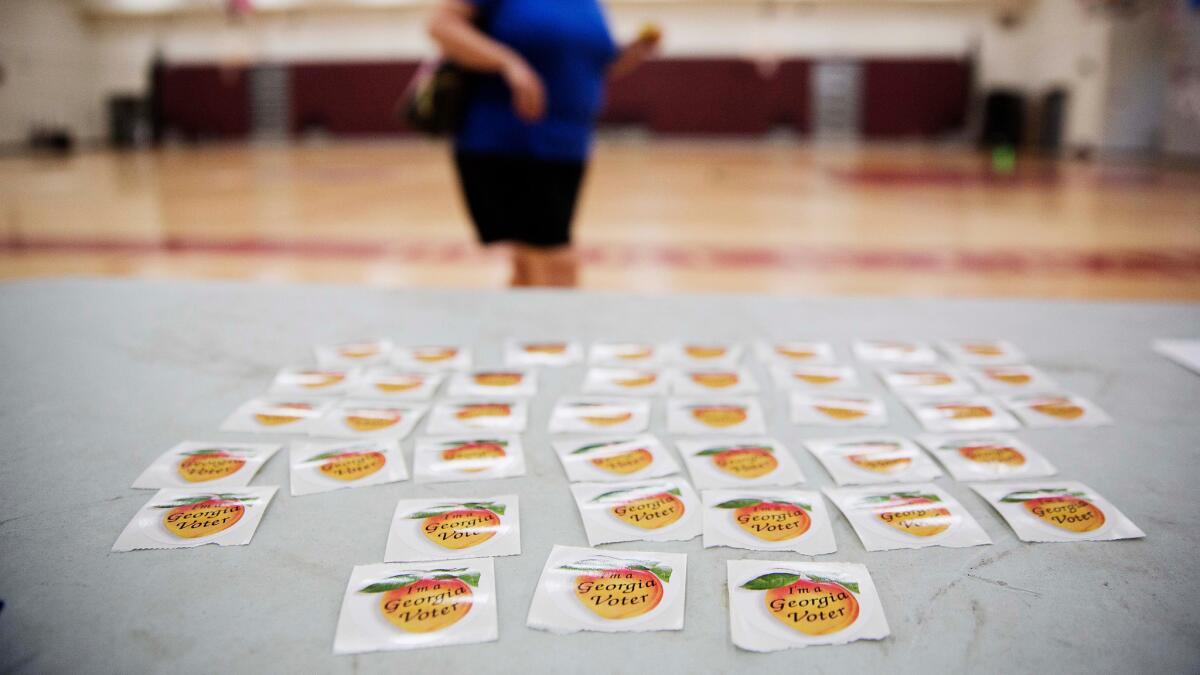 Stickers reading "I'm a Georgia Voter" sit on a table as a voter leaves a polling site after casting a ballot Tuesday, July 26, 2016, in Atlanta.