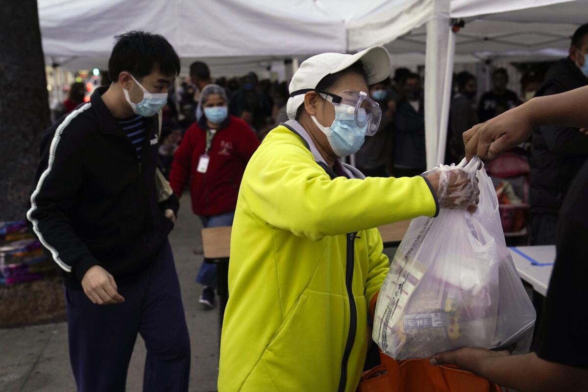 A woman receives a bag of groceries at a food bank at the Los Angeles Boys & Girls Club in Lincoln Heights.