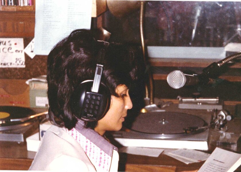 Hassina Leelarathna wears headphones and speaks into a microphone