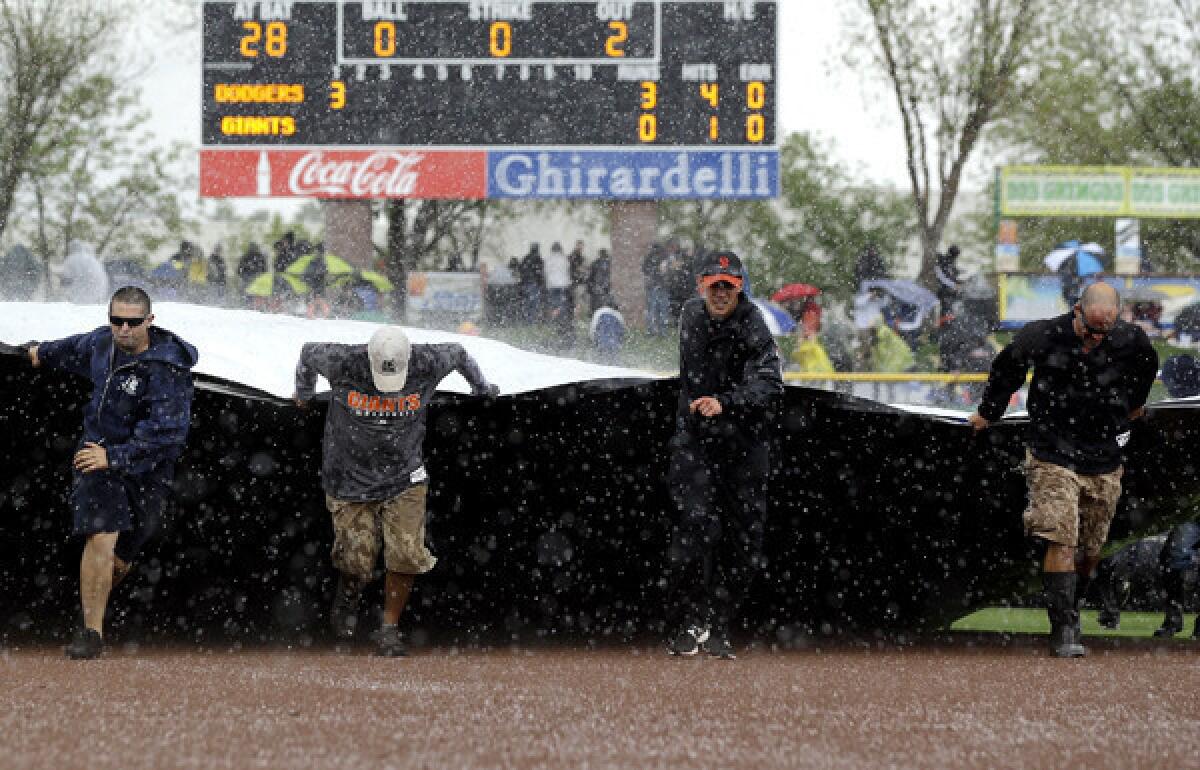 The grounds crew covers the field during a brief hailstorm that stopped Friday's exhibition game between the Dodgers and Giants.