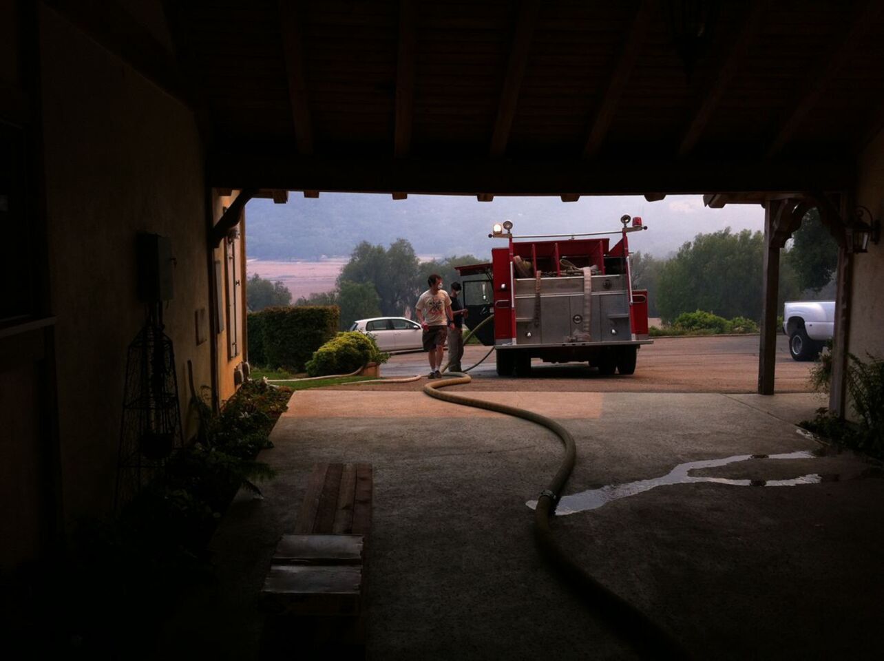 As dawn breaks Saturday and cooler onshore winds push the Springs fire back on itself, a man walks past a fire truck stationed in the driveway of a home to provide protection for a Thousand Oaks neighborhood.