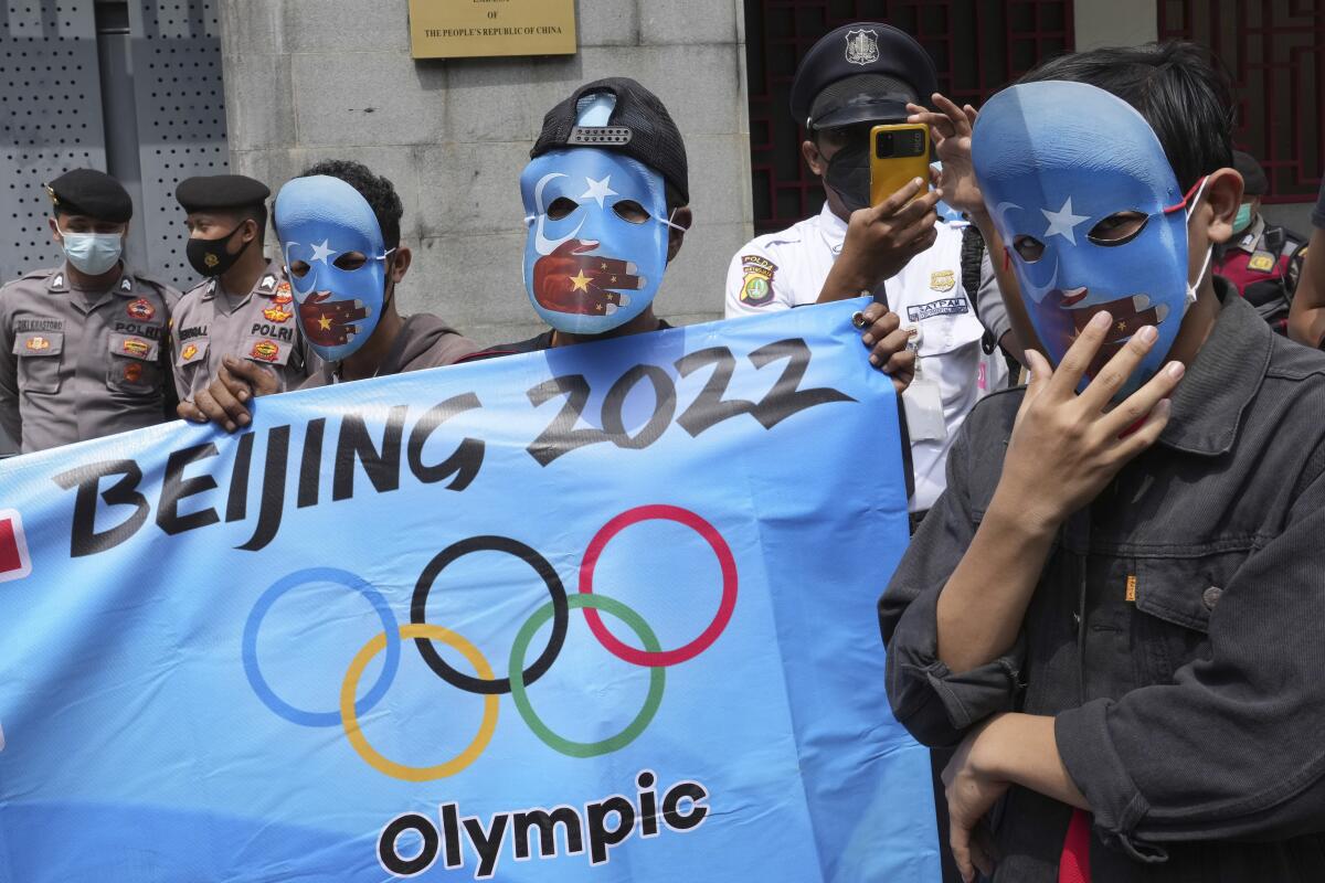 Student activists wear masks with the colors of the pro-independence East Turkistan flag during a rally to protest the Beijing 2022 Winter Olympic Games, outside the Chinese Embassy in Jakarta, Indonesia, Friday, Jan. 14, 2022. Dozens of students staged the rally demanding the cancellation of the Beijing Olympics over alleged human rights violations against Muslim Uyghur ethnic minority in China's region of Xinjiang. (AP Photo/Tatan Syuflana)