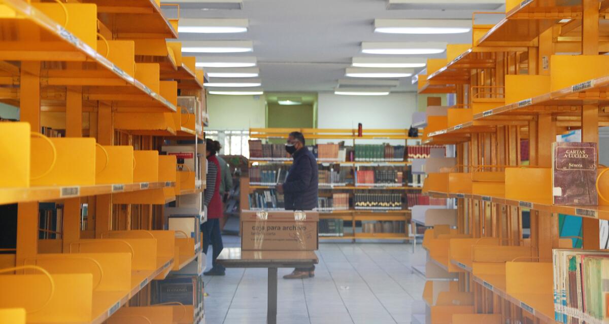Shelves look partially empty as employees arrange books in boxes at the Benito Juárez library.