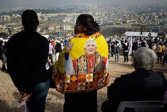 A pilgrim wearing a cape with the image of Pope Benedict XVI attends a Mass led by the pontiff in Nazareth, the boyhood town of Jesus that is now an Arab-Israeli city. Tens of thousands of pilgrims with flags and banners unfurled thronged to the beat of drums and tambourines to witness Pope Benedict XVI celebrating his largest Mass in the Holy Land.