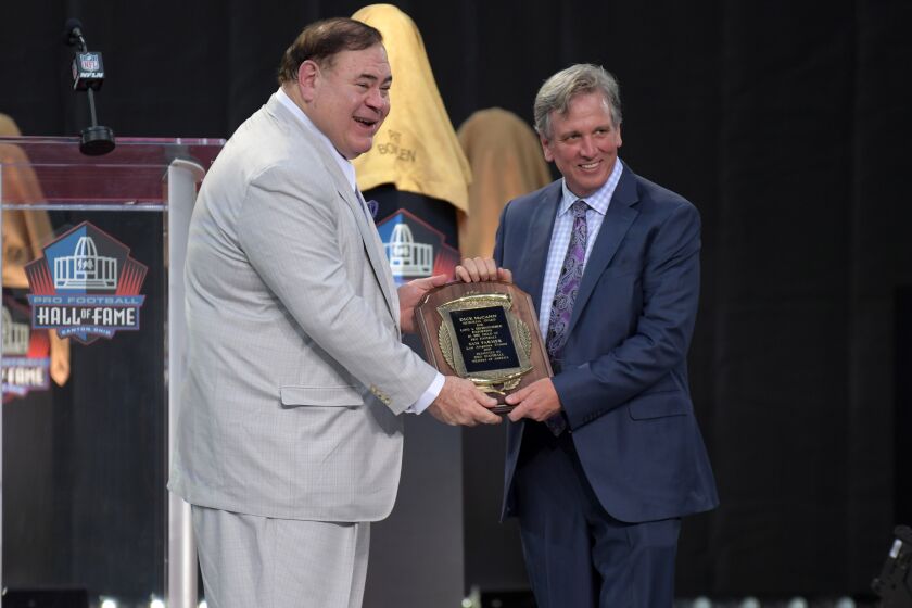 Pro Football Hall of Fame president David Baker hands Sam Farmer the Dick McCann Award.