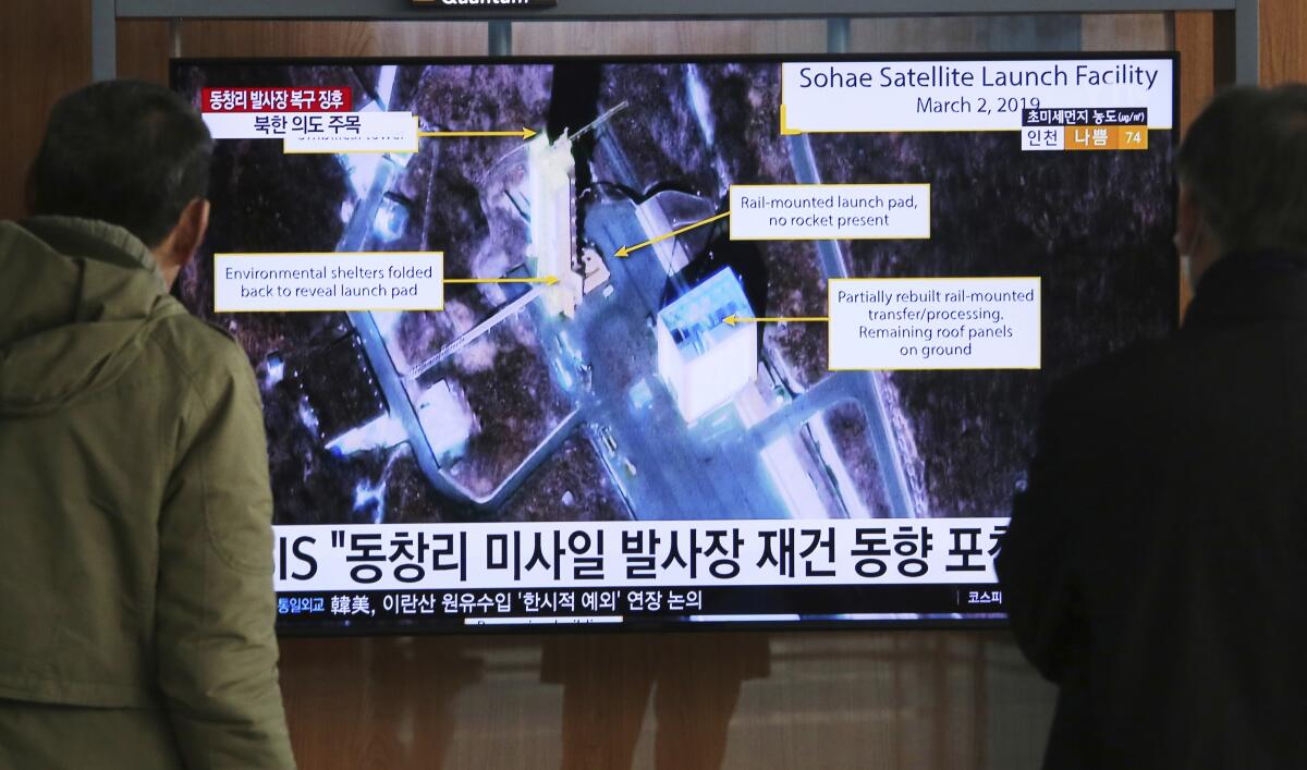 People in Seoul watch a TV screen showing an image of a North Korean rocket launch station.
