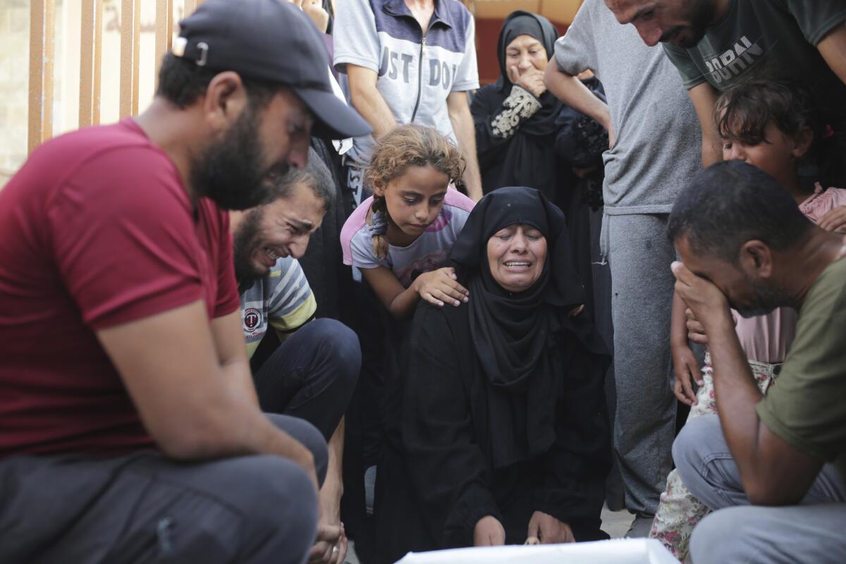 Mourners kneel and cry while grouped around a victim of Israeli shelling
