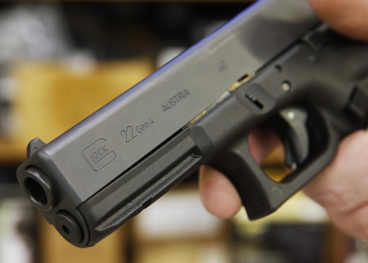 A person holds a Glock .22 handgun.   