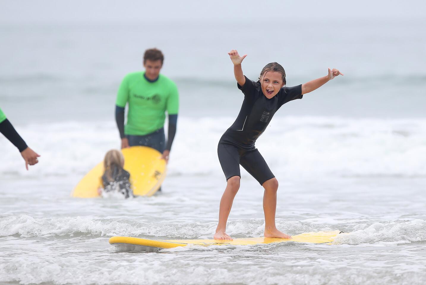 A youngster rides a small wave during an Erik Nelsen Surf Camp in Newport Beach on Tuesday.