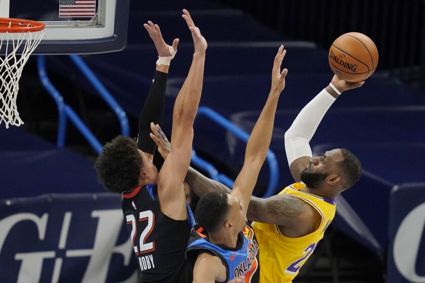 Los Angeles Lakers forward LeBron James, right, shoots as Oklahoma City Thunder forward Isaiah Roby (22) and forward Darius Bazley defend during the first half of an NBA basketball game Wednesday, Jan. 13, 2021, in Oklahoma City. (AP Photo/Sue Ogrocki)