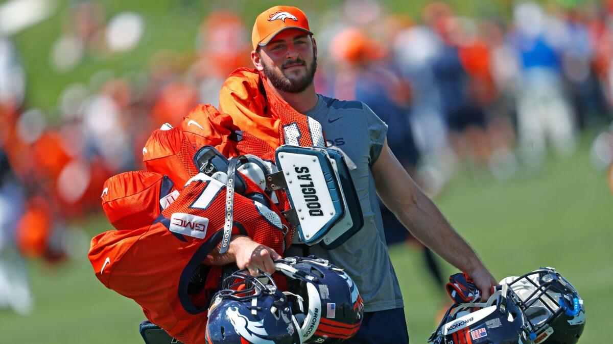 Denver Broncos tight end Jake Butt carries the helmets and pads of veteran players after drills at an NFL training camp in July.
