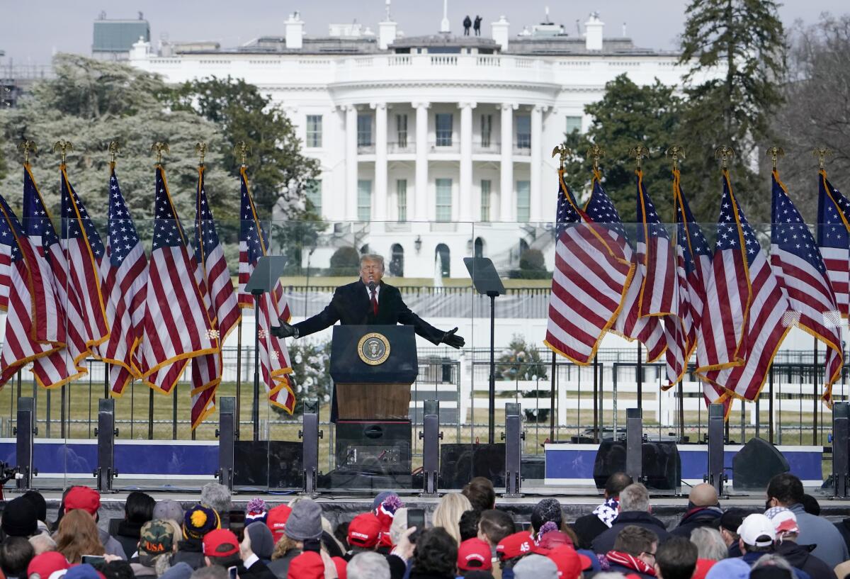 Trump speaks to a crowd on a stage in front of the White House.