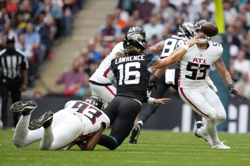 Jacksonville Jaguars quarterback Trevor Lawrence (16) passes the ball as he is tackled by Atlanta Falcons defensive tackle Calais Campbell (93) during an NFL football game between the Atlanta Falcons and the Jacksonville Jaguars at Wembley stadium in London, Sunday, Oct. 1, 2023. (AP Photo/Kirsty Wigglesworth)