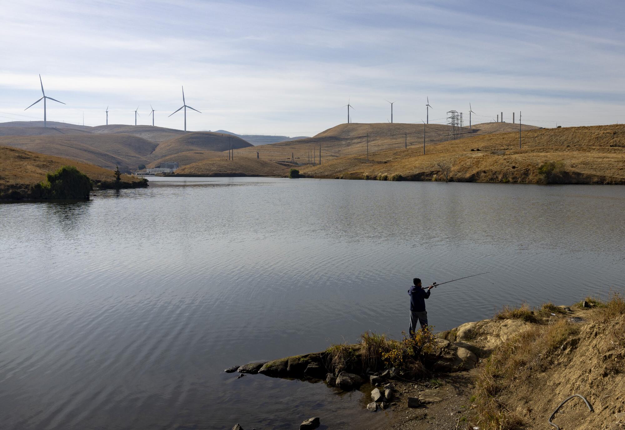 An angler casts into a reservoir.