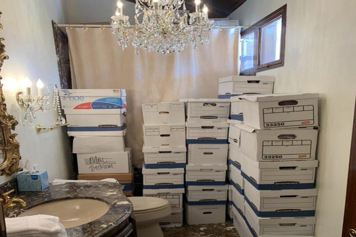 Stacks of records boxes under a chandelier in a bathroom.