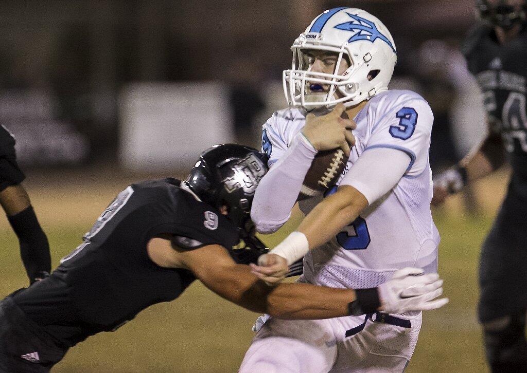 Corona del Mar High quarterback Chase Garbers is tackled by Buena Park's AJ Allen during a CIF Southern Section Southwest Division quarterfinal game at Buena Park on Friday.
