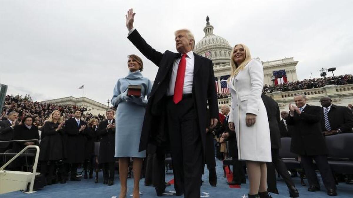 President Trump waves after taking the oath of office as his wife Melania, left, holds a Bible, and daughter Tiffany looks out to the crowd on Friday in Washington.