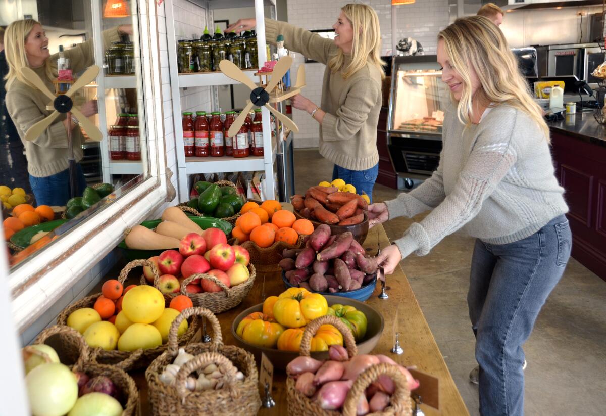Casey Walters, back, and Hayley McDonald arrange farm fresh produce at Sections Fine Meats.