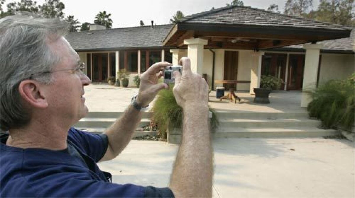 SURVIVOR: Dr. David Roland takes a snapshot of his house in Rancho Santa Fe, Calif., which had been sprayed with fire retardant by a private firm and emerged from the flames intact.