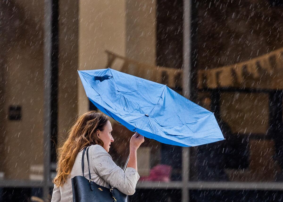 A woman's umbrella flips inside out.