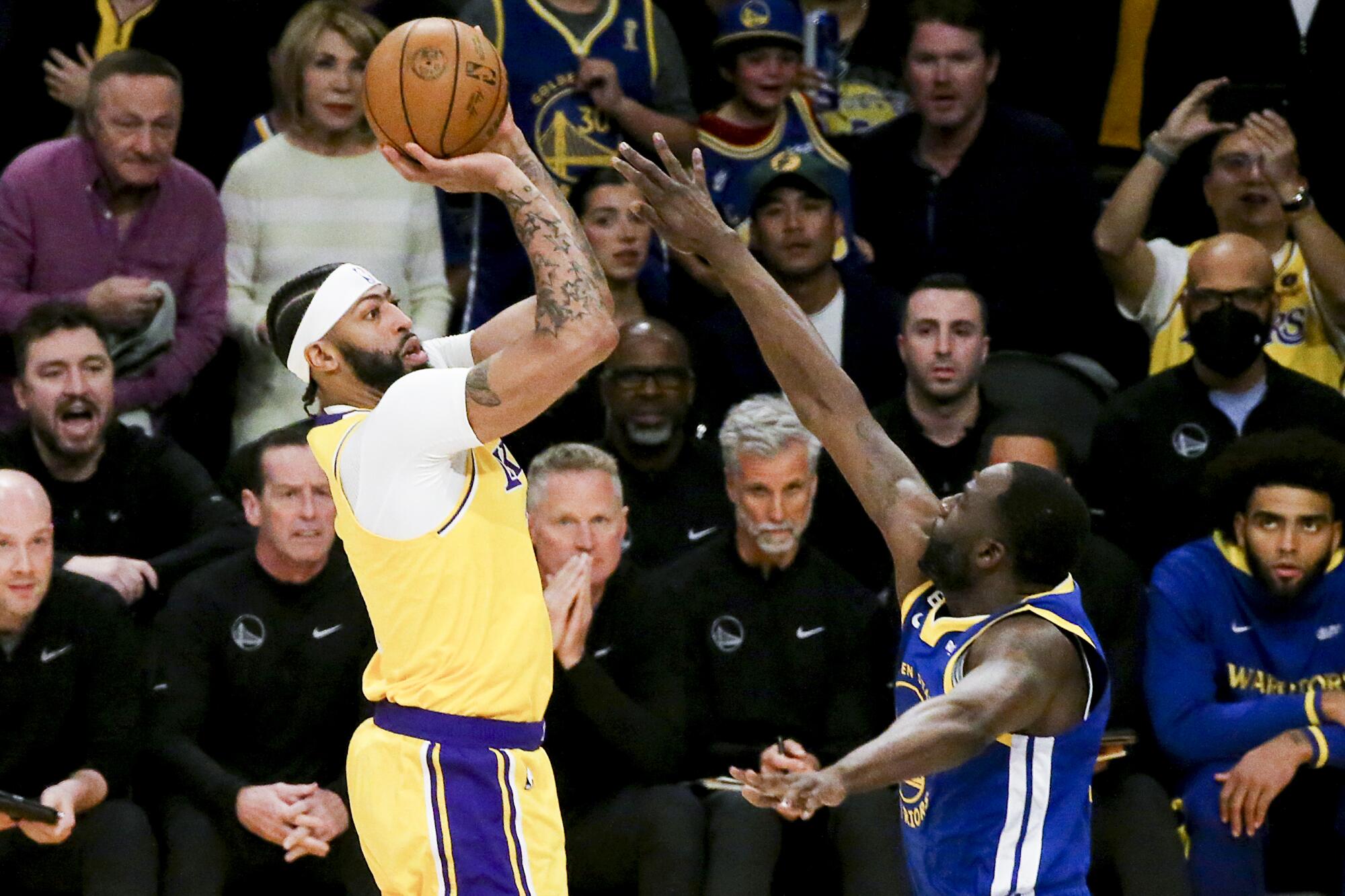 Lakers forward Anthony Davis, left, shoots over an outstretched arm of Warriors forward Draymond Green.